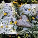 Aufgeklapptes Buch mit im bunten Blütenmeer mit Herz