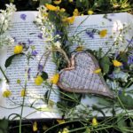 Aufgeklapptes Buch mit im bunten Blütenmeer mit Herz